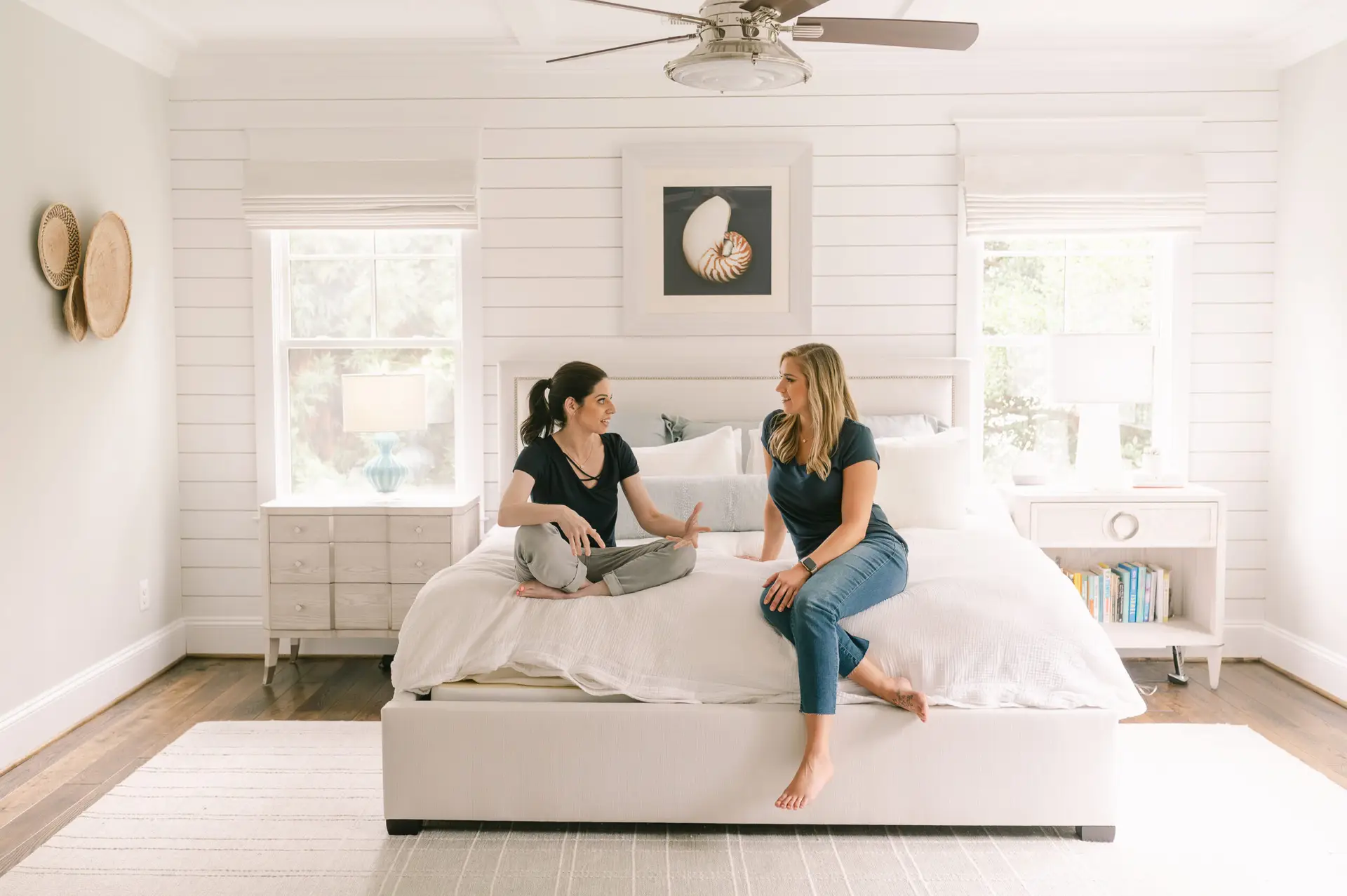 Two baby proofers sitting on a bed, discussing safety principles.