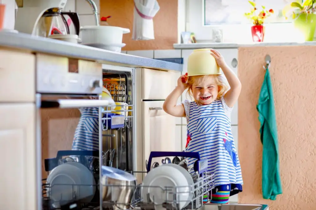 Where To Start Baby Proofing (Without Losing Your Mind) Toddler in kitchen playing with bowl on her head.